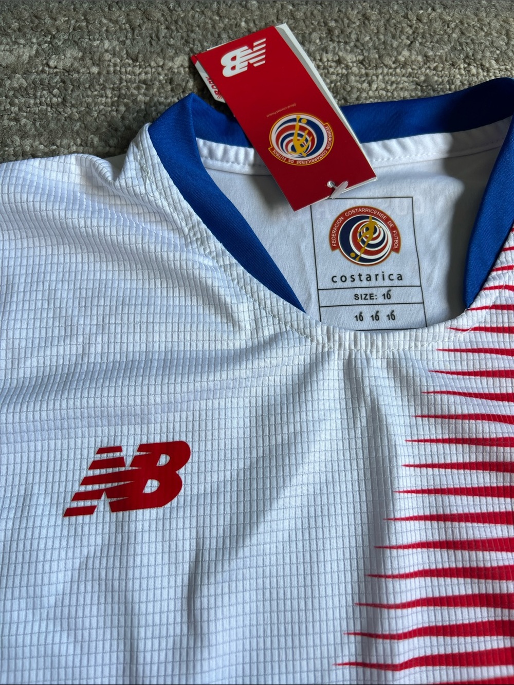 New Balance Kids CostaRica White Jersey with Red Diagonal Stripe and Blue Trim